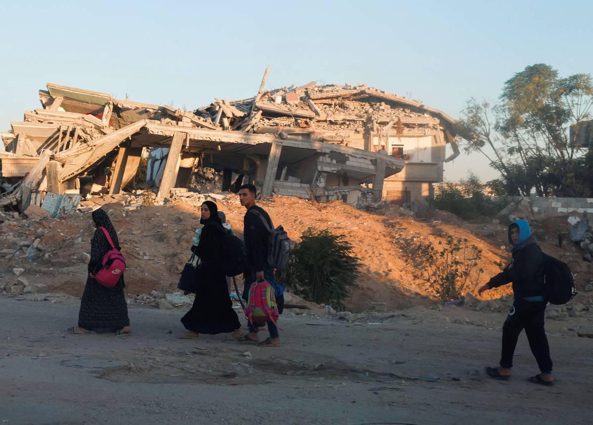 أسرة فلسطينية أمام مبان مدمرة في خان يونس بغزة