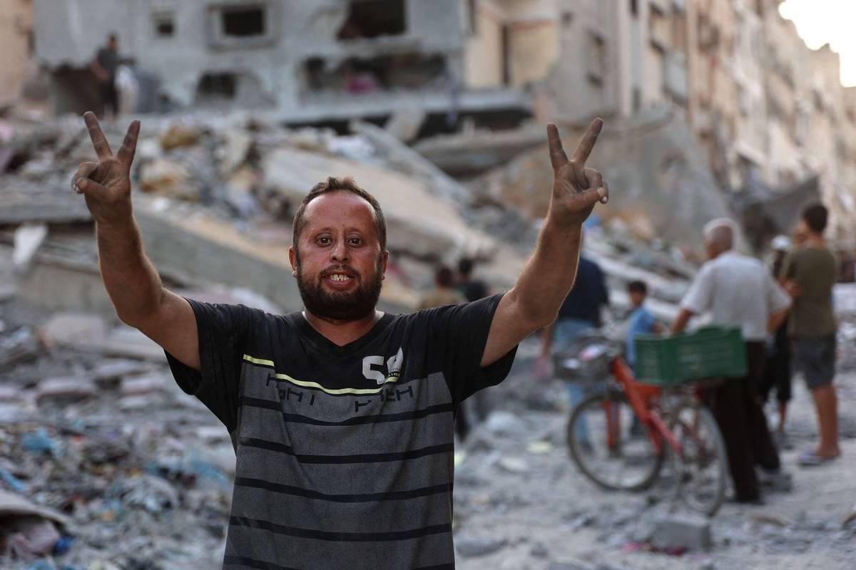 فلسطيني يرفع علامة النصر أمام مبنى مدمر في غزة