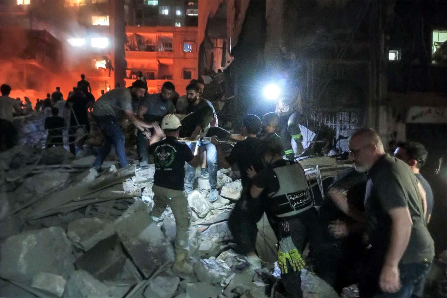 Lebanese civil defence members and other people inspect the site of an Israeli airstrike on the Basta neighbourhood of Beirut