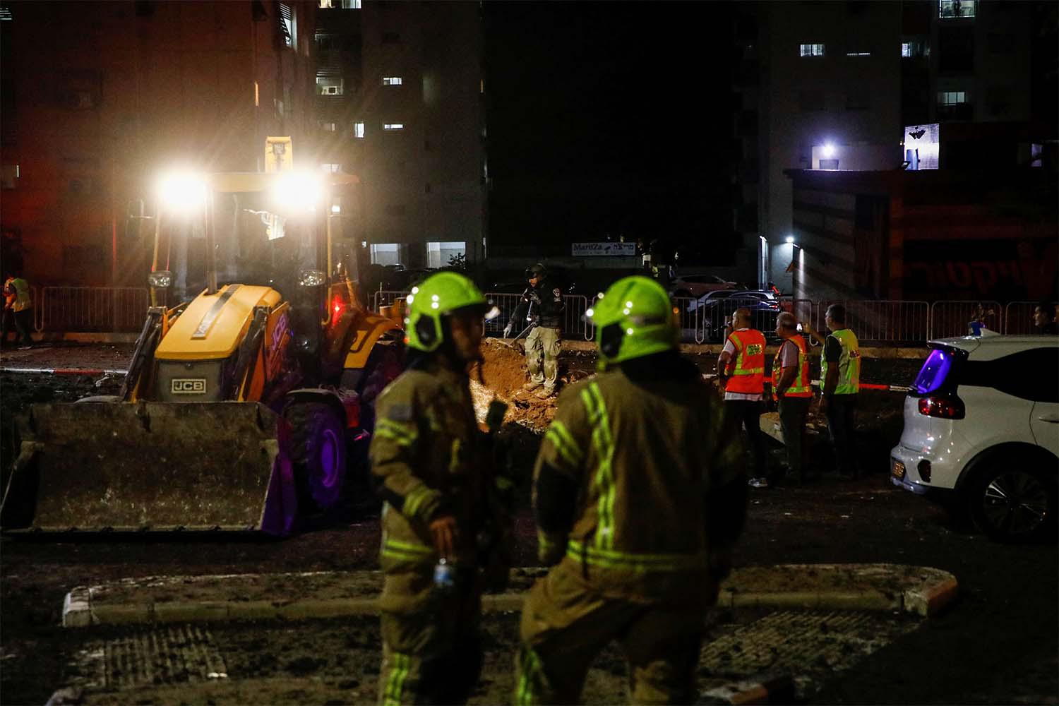 Israeli rescue force members inspect the site where a projectile fell amid cross-border hostilities between Hezbollah and Israel in Haifa