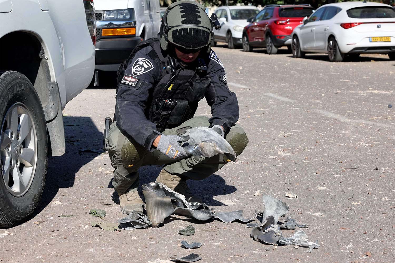 An Israeli policeman gathers debris at the site of a rocket attack, fired from Lebanon, in Kibbutz of Maagan Michael