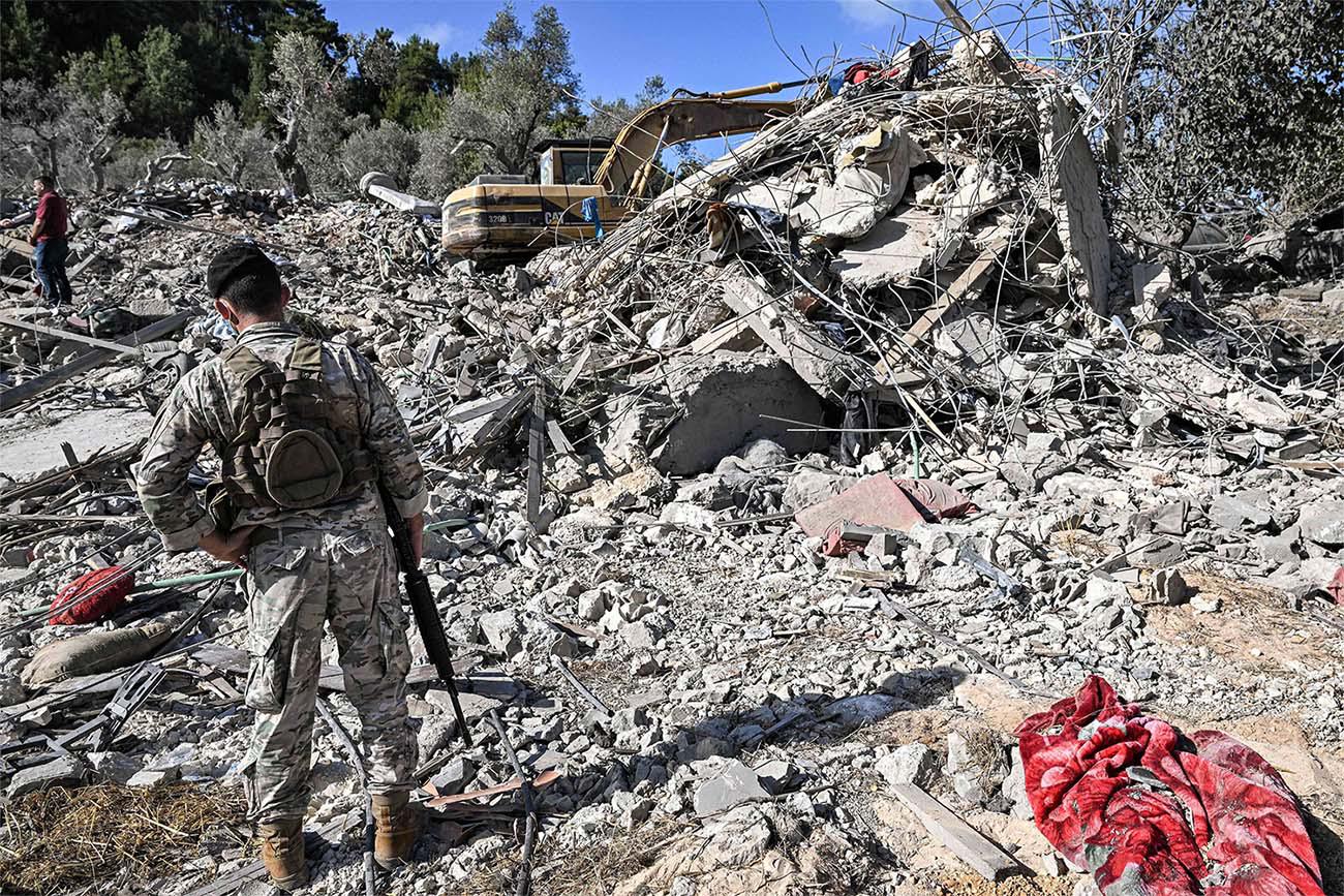 A Lebabese army soldier stands by the rubble of a destroyed building at the site of a previous Israeli air strike on the village of Aito in northern Lebanon