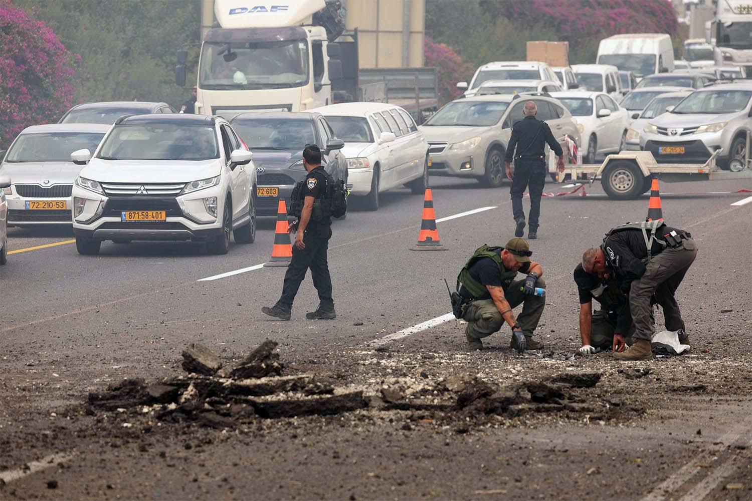Members of Israeli security forces inspect the impact site of a reported rocket fired from Lebanon on central Israel