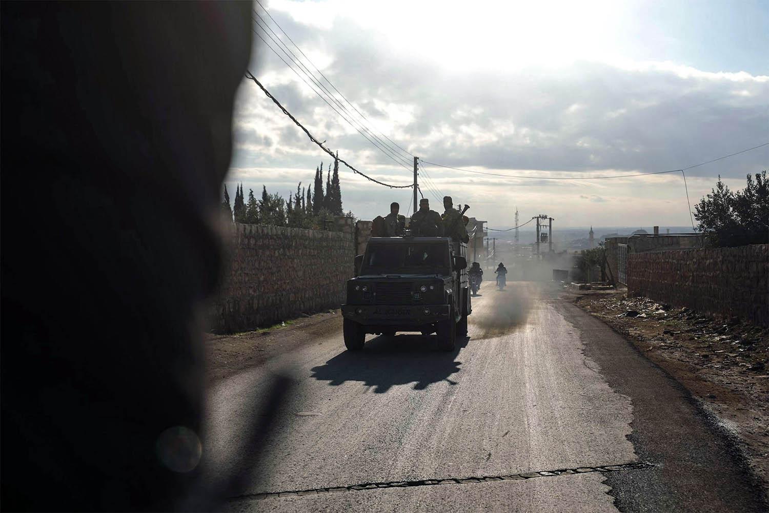Fighters from Hayat Tahrir al-Sham (HTS) ride in military vehicles in the eastern outskirts of the town of Atarib,