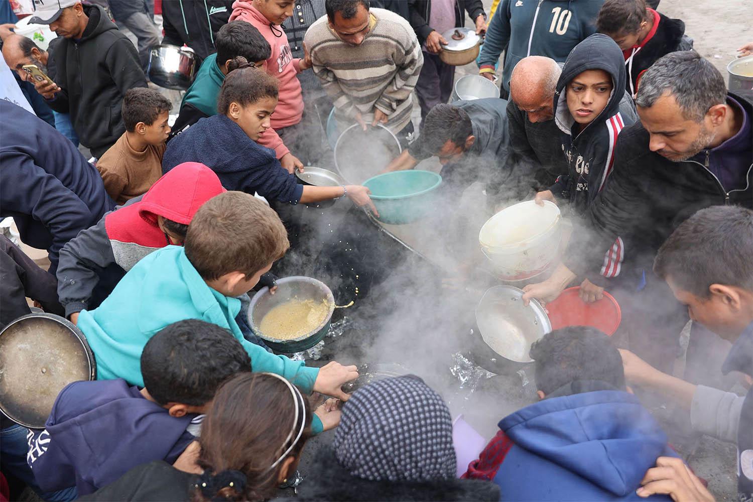 alestinians queue to receive a food ration outside a distribution center west of Gaza City