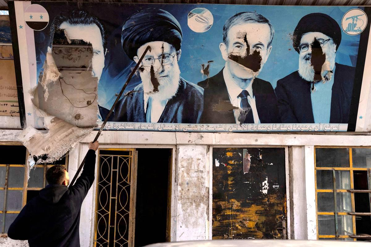جدارية محطمة للرئيسين السوريين السابقين حافظ الأسد وبشار الأسد وزعيم حزب الله السابق حسن نصرالله والمرشد الإيراني الأعلى علي خامنئي في قرية بالقرب من حلب