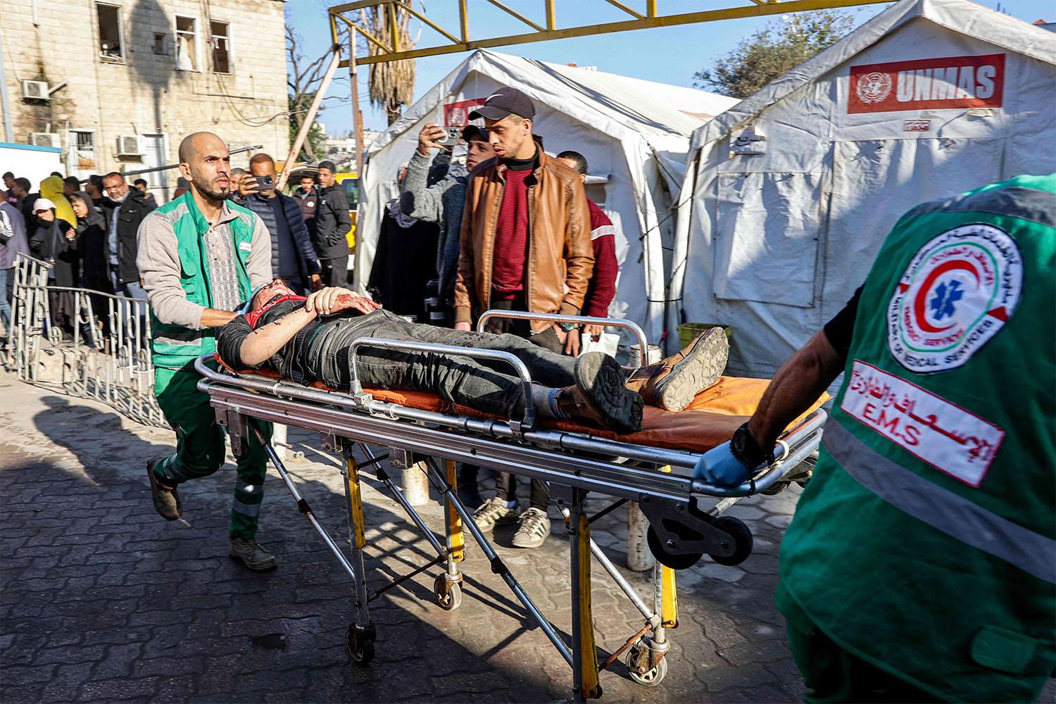 Paramedics transport on a gurney a person who was injured in a reported strike on a Palestinian civilian vehicle by Israeli forces