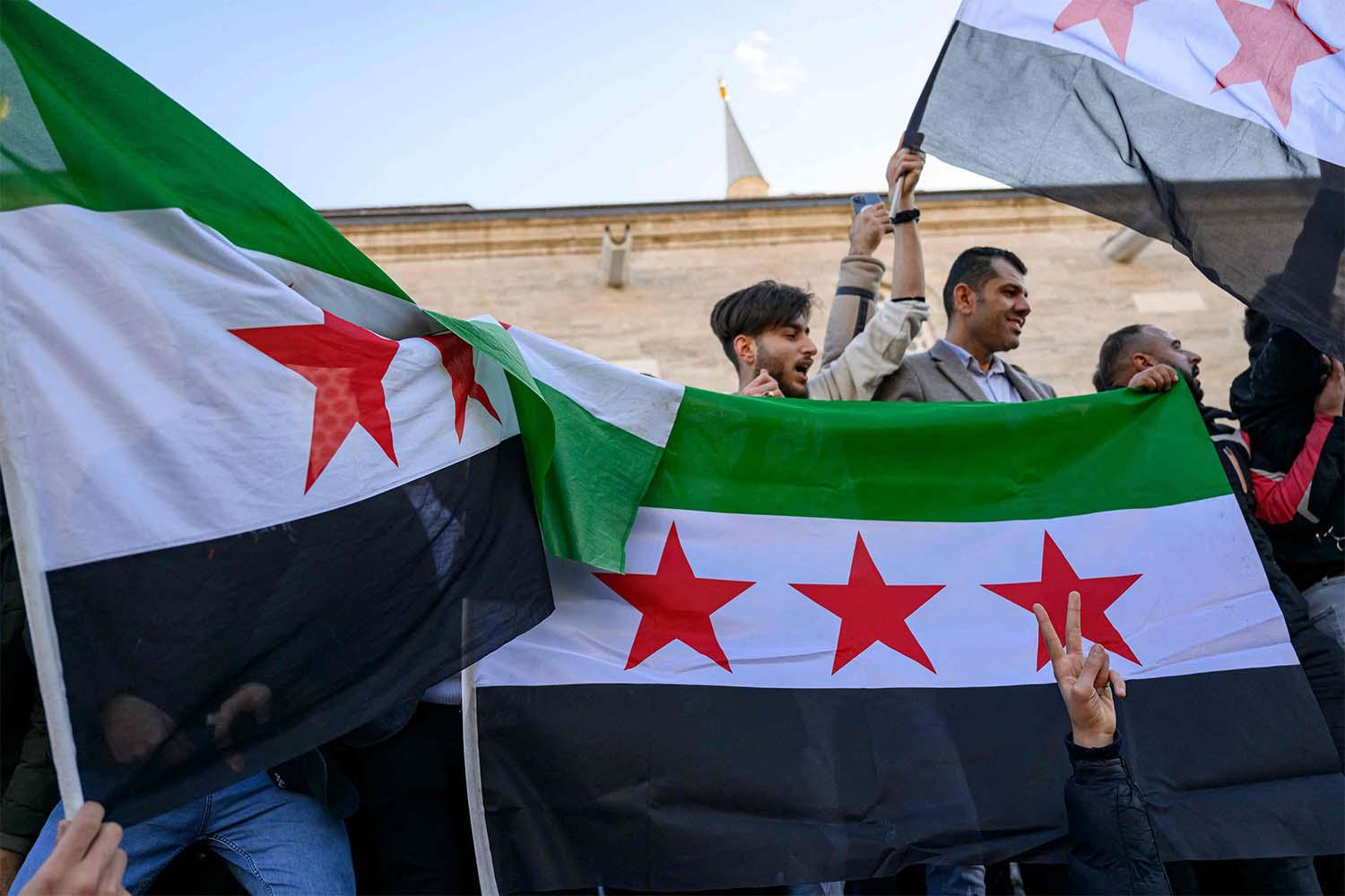 Syrian residents in Turkey hold Syrian flags as they celebrate the end of the Baath rule in Syria 