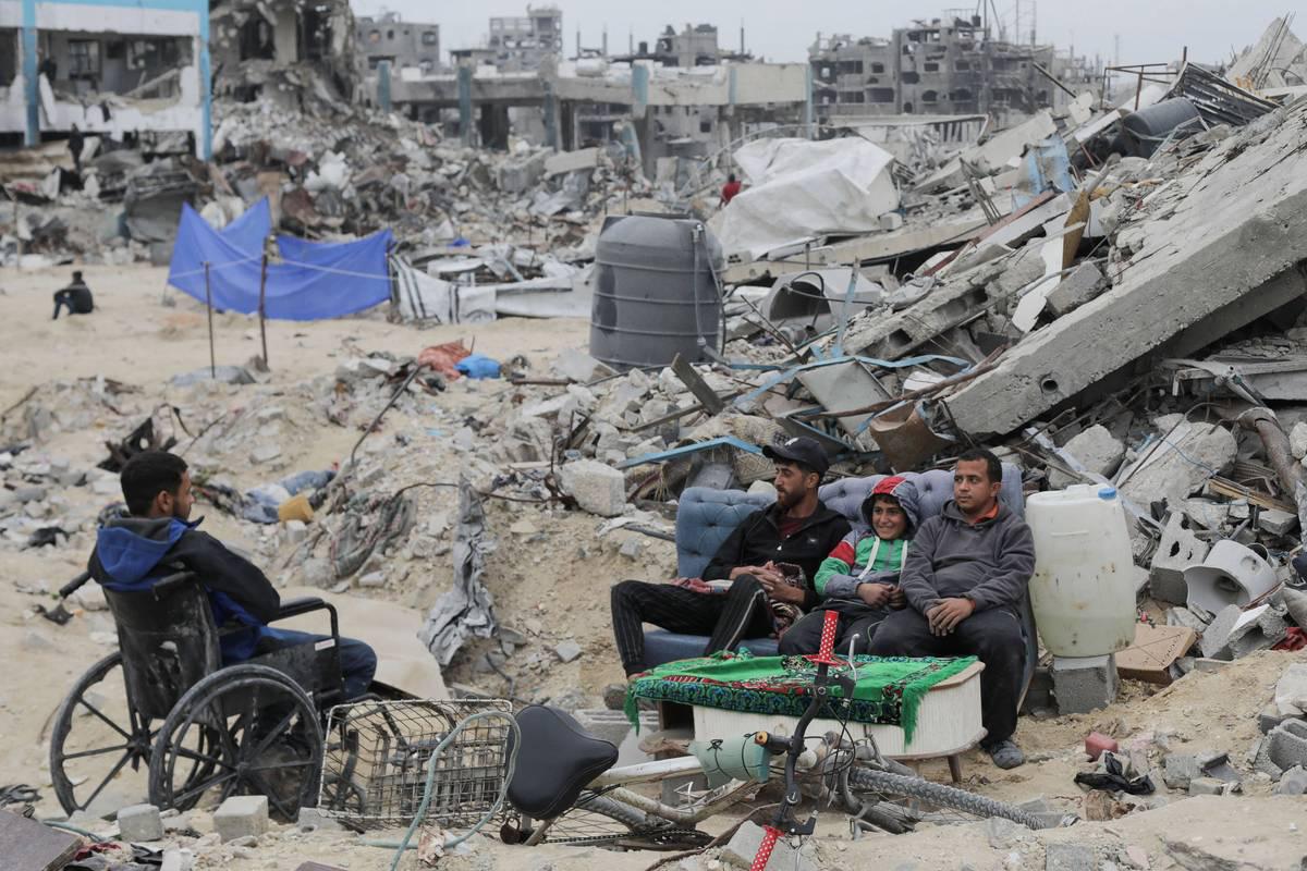فلسطينيون يجلسون أمام انقاض منازلهم في غزة