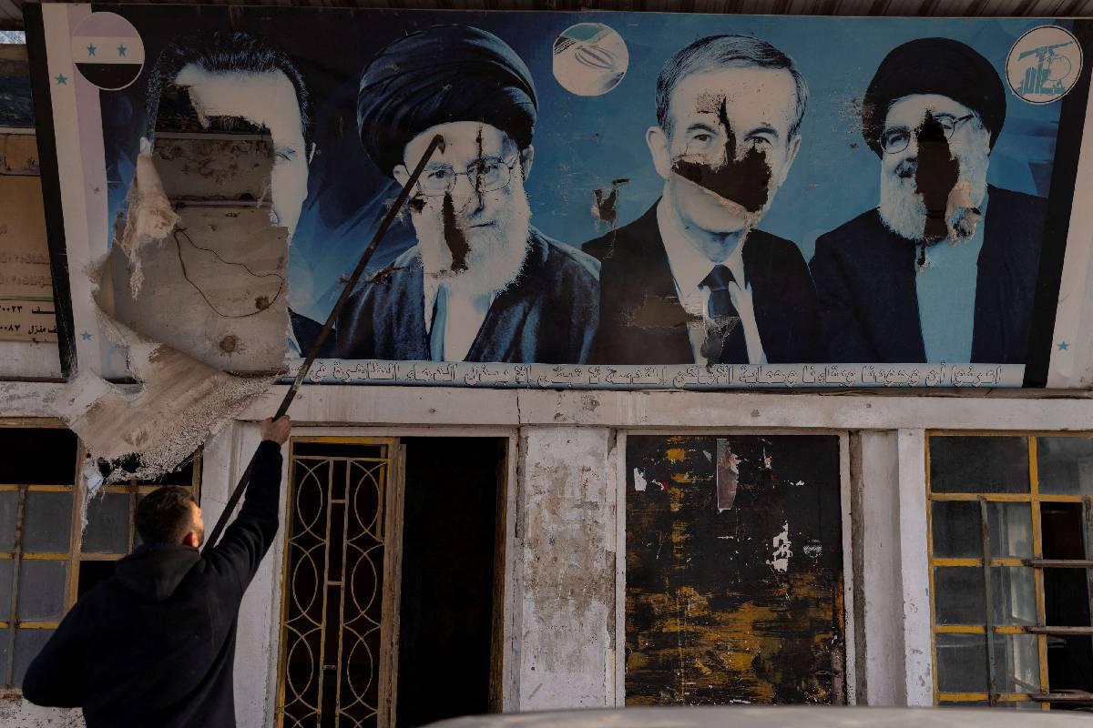 سوري يخرب صورا لنصرالله والأسد الأب والابن وخامنئي