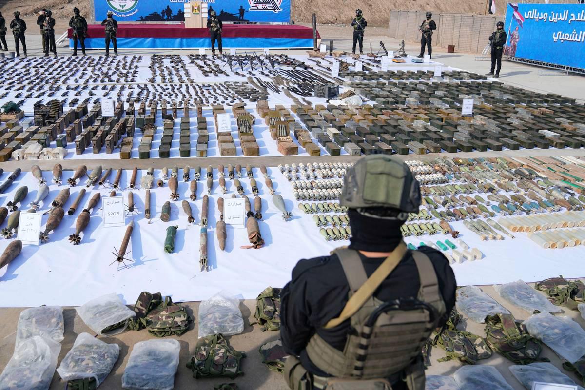 مقاتل من الحشد الشعبي في العراق يستعرض كمية من الأسلحة المصادرة في عملية تفتيش أمنية