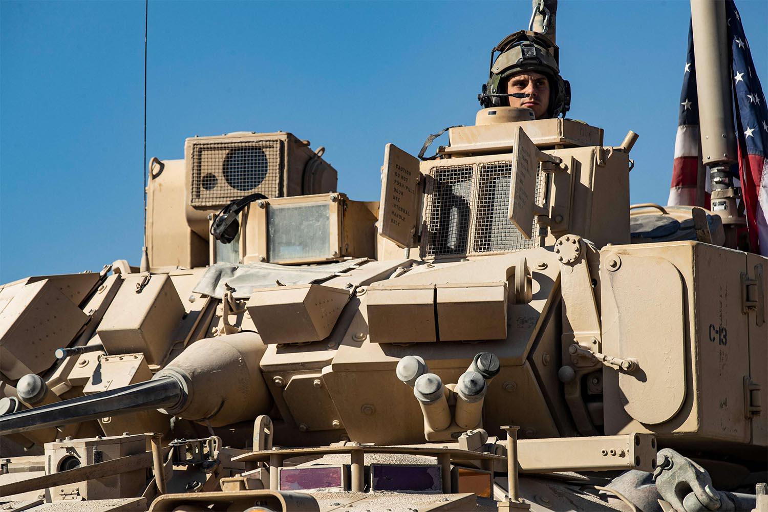 A US soldier monitors the area as troops patrol oil fields near Syria's northeastern border with Turkey