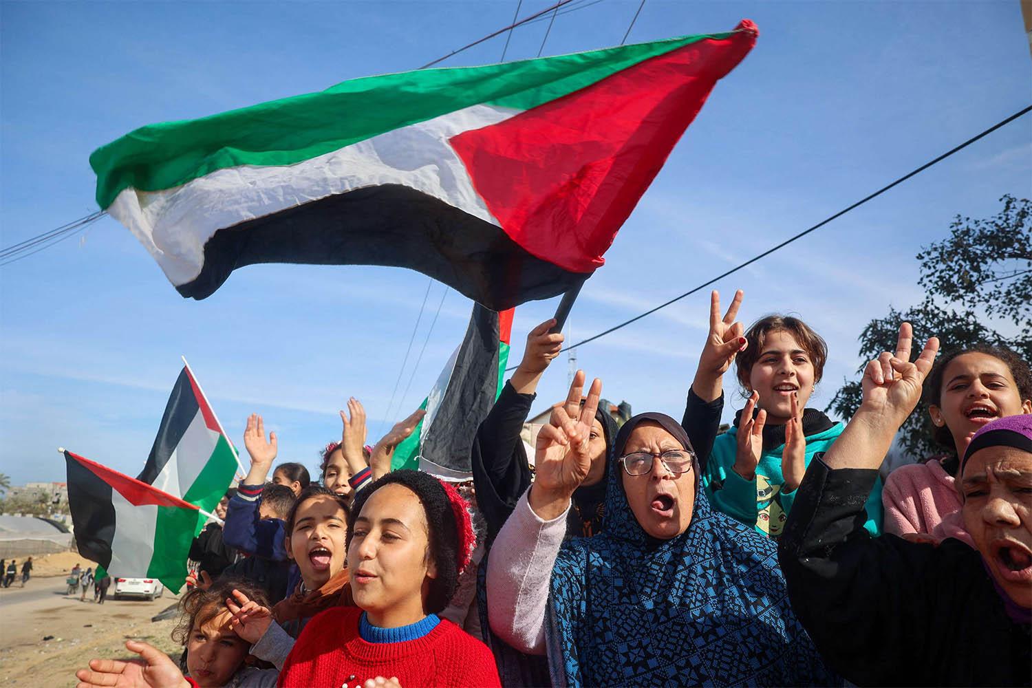 Displaced Palestinians wave national flags as they return to Rafah