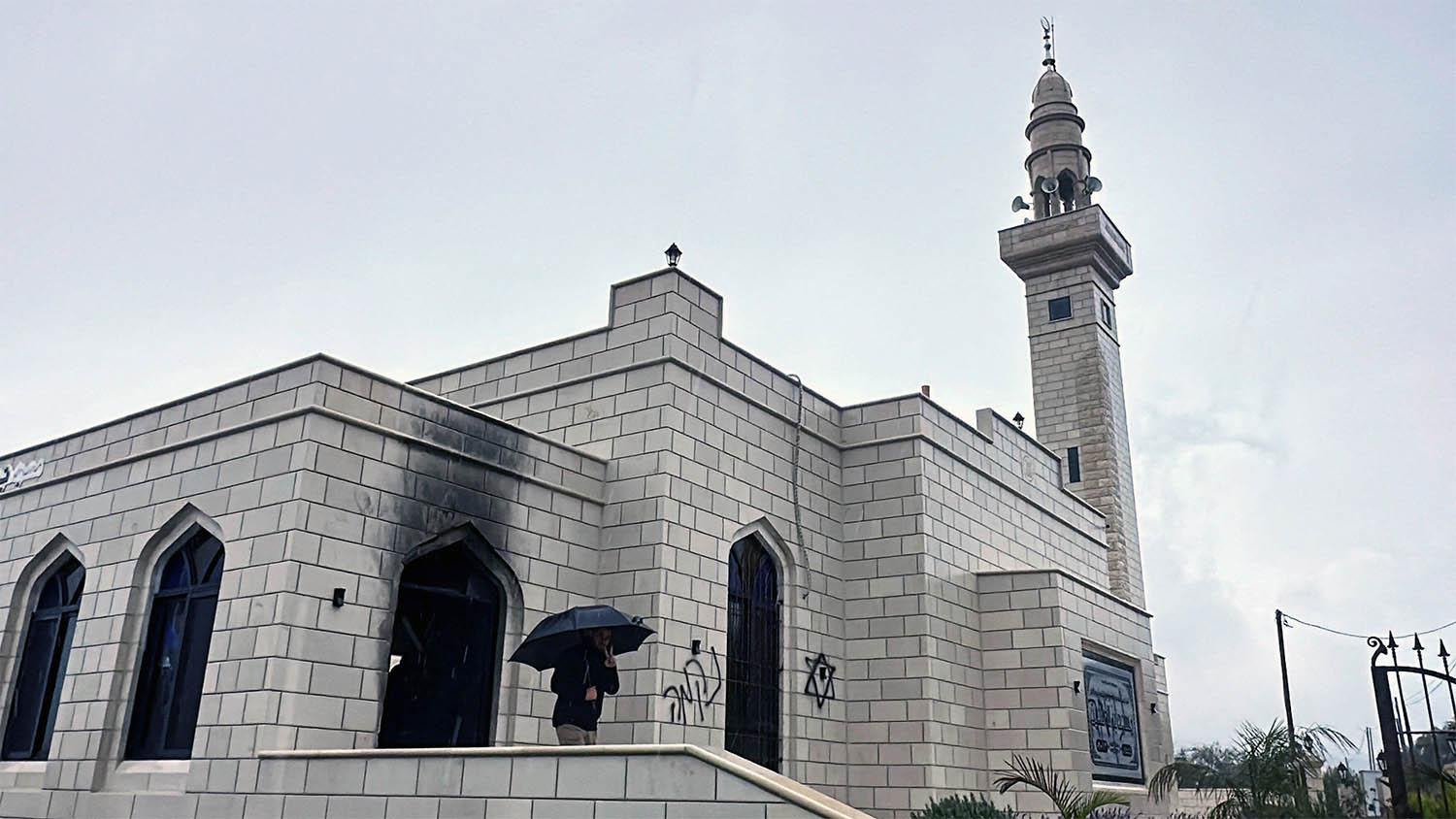 A person stands at a damaged mosque burned by Israeli settlers near Salfit in the Israeli-occupied West Bank 