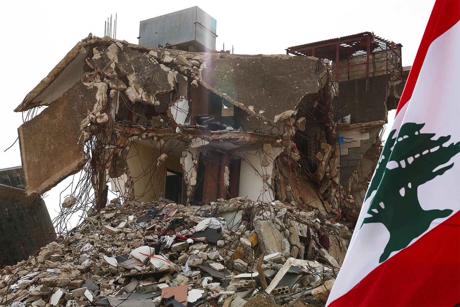 ebanon's flag next to a damaged building in the southern Lebanese village of Kfar Kila
