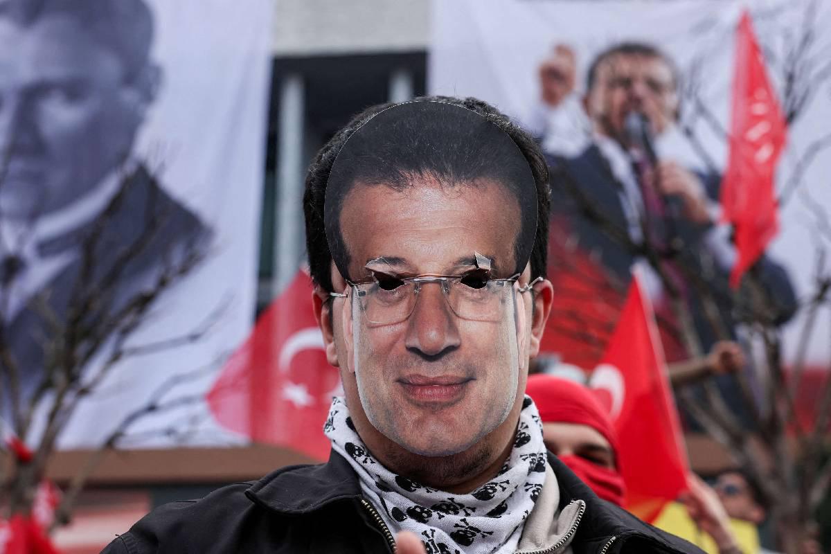 متظاهر يرتدي قناعا لأكرم إمام أوغلو في تظاهرة في اسطنبول