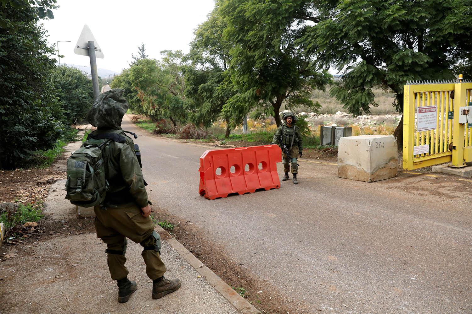Israeli soldiers guard near an barrier blocking an entrance leading to the border with Lebanon