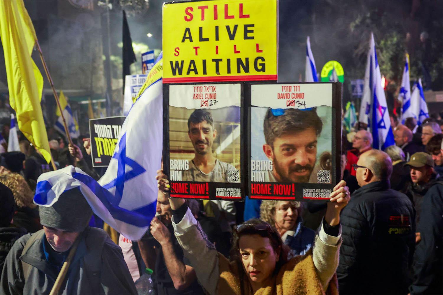 Israeli protesters lift placards during a rally calling on the government for a deal that would bring all the remaining captives back