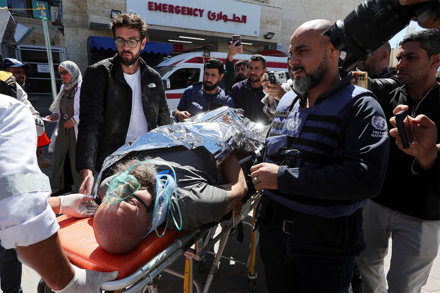 A foreign worker, who was wounded in an Israeli airstrike on a UN headquarters is brought into Al-Aqsa Martyrs hospital, in Deir Al-Balah