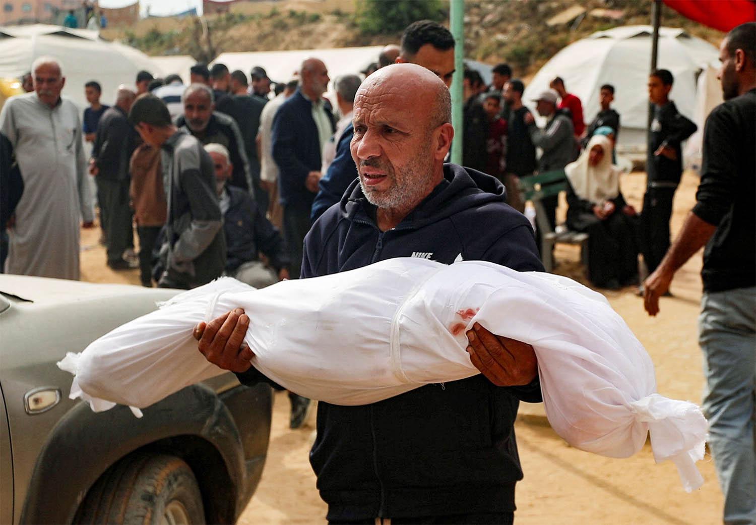 A man reacts holding the body of a Palestinian child killed in Israeli strikes on Gaza
