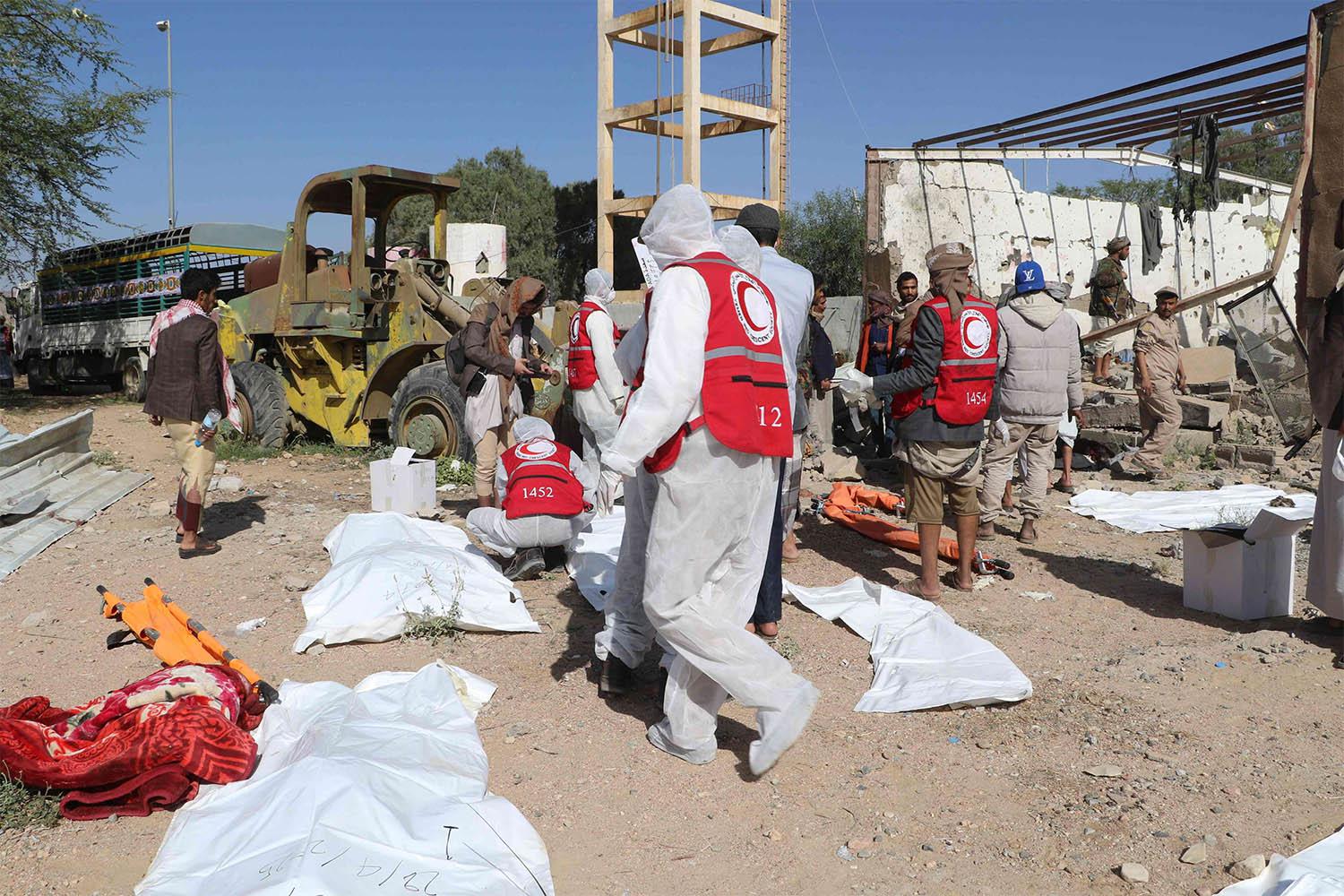 Yemeni rescuers transport the bodies of victims pulled from the rubble of a building hit in US strikes in Saada