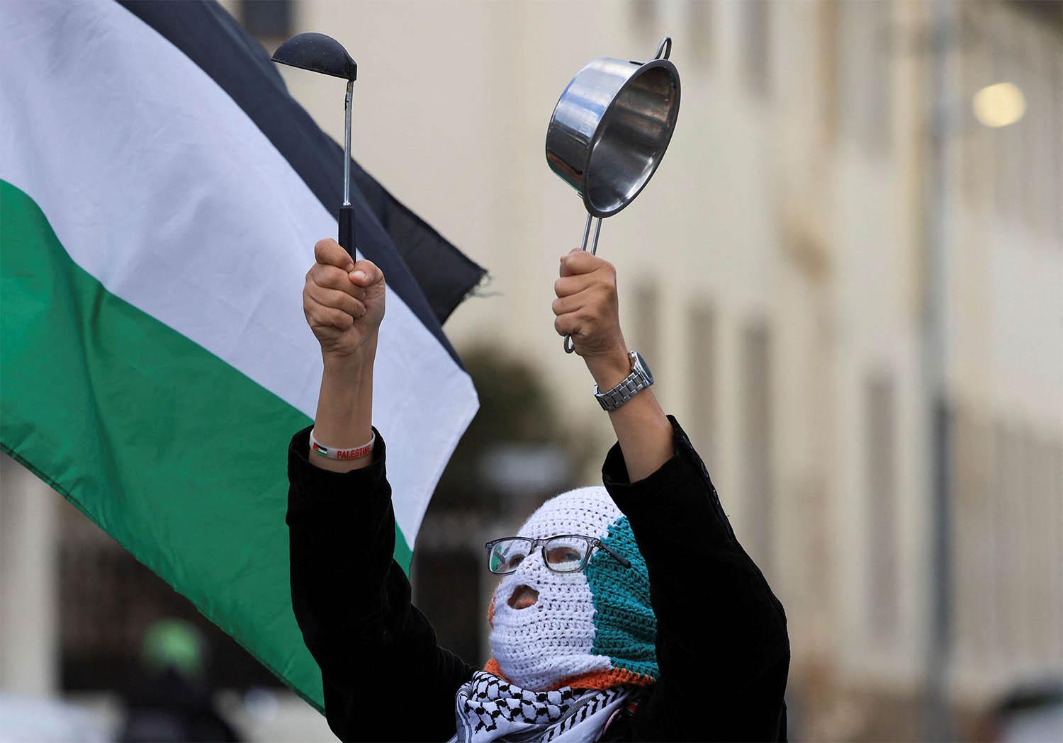 A pro-Palestinian activist makes noise with a pot in a protest over the hunger crisis in Gaza, outside the parliament in Cape Town