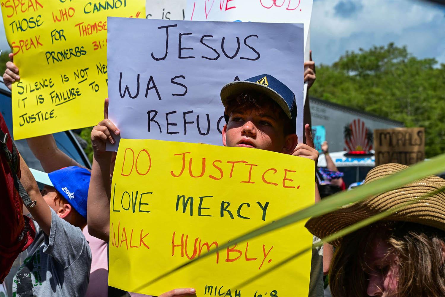 Demonstrators hold signs as they protest US President President Donald Trumps visit to a migrant detention center, dubbed Alligator Alcatraz, located in Ochopee, Florida 