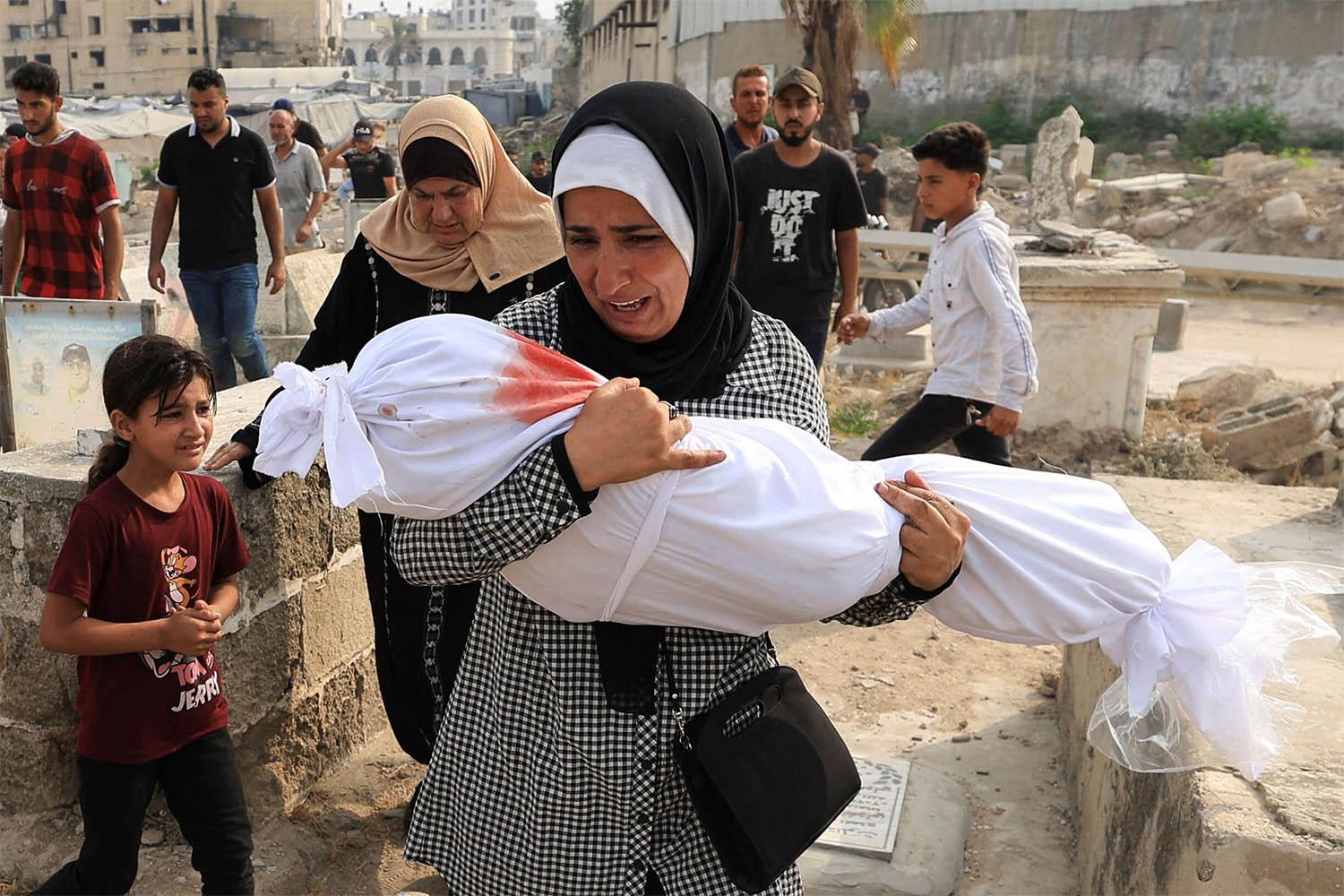 Palestinian woman Soha Tafesh carries the body of her granddaughter Sarah Abu Daf, who was killed in an early morning Israeli strike on a house