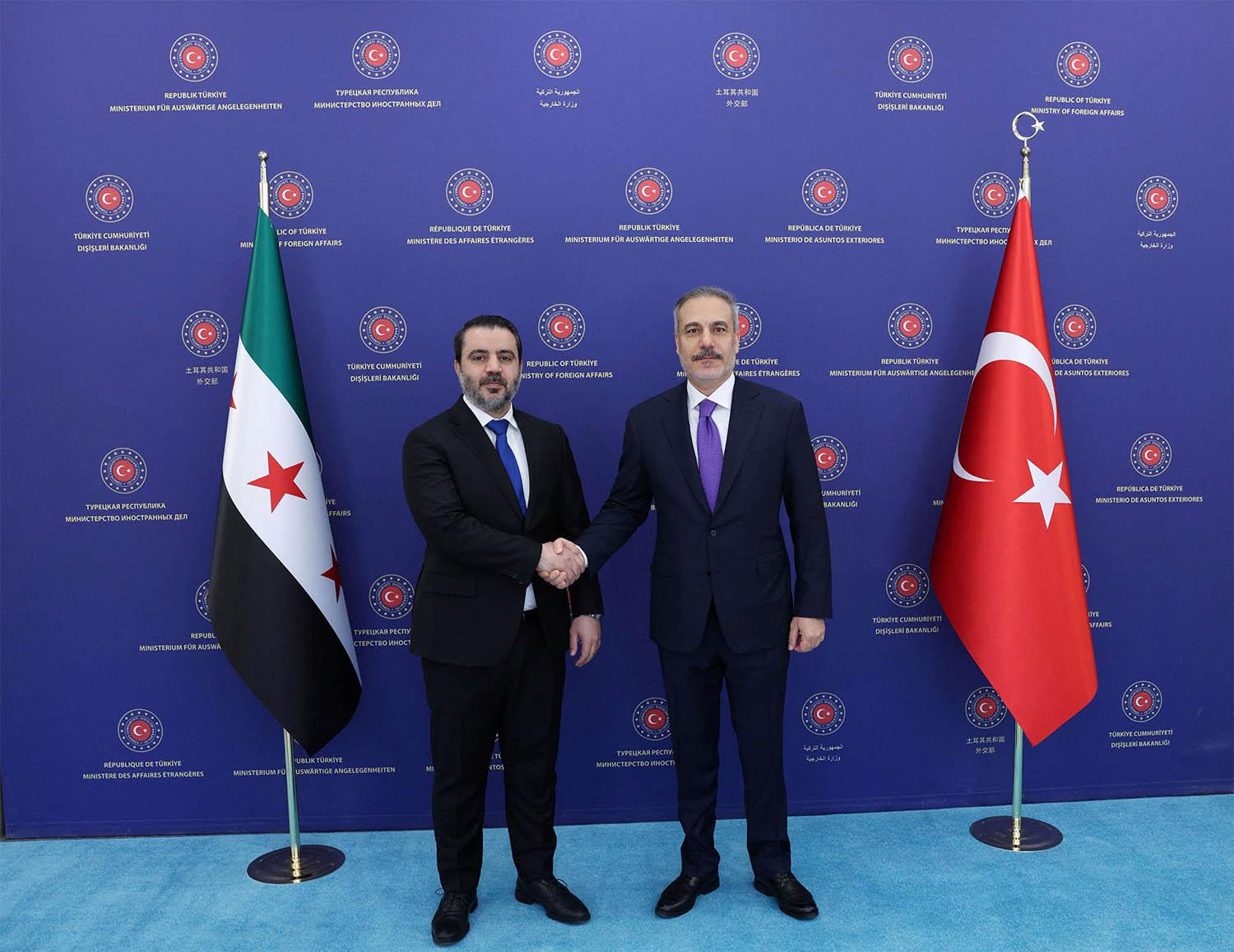 Turkish Foreign Minister Hakan Fidan shakes hands with his Syrian counterpart Asaad Hassan al-Shibani in Ankara