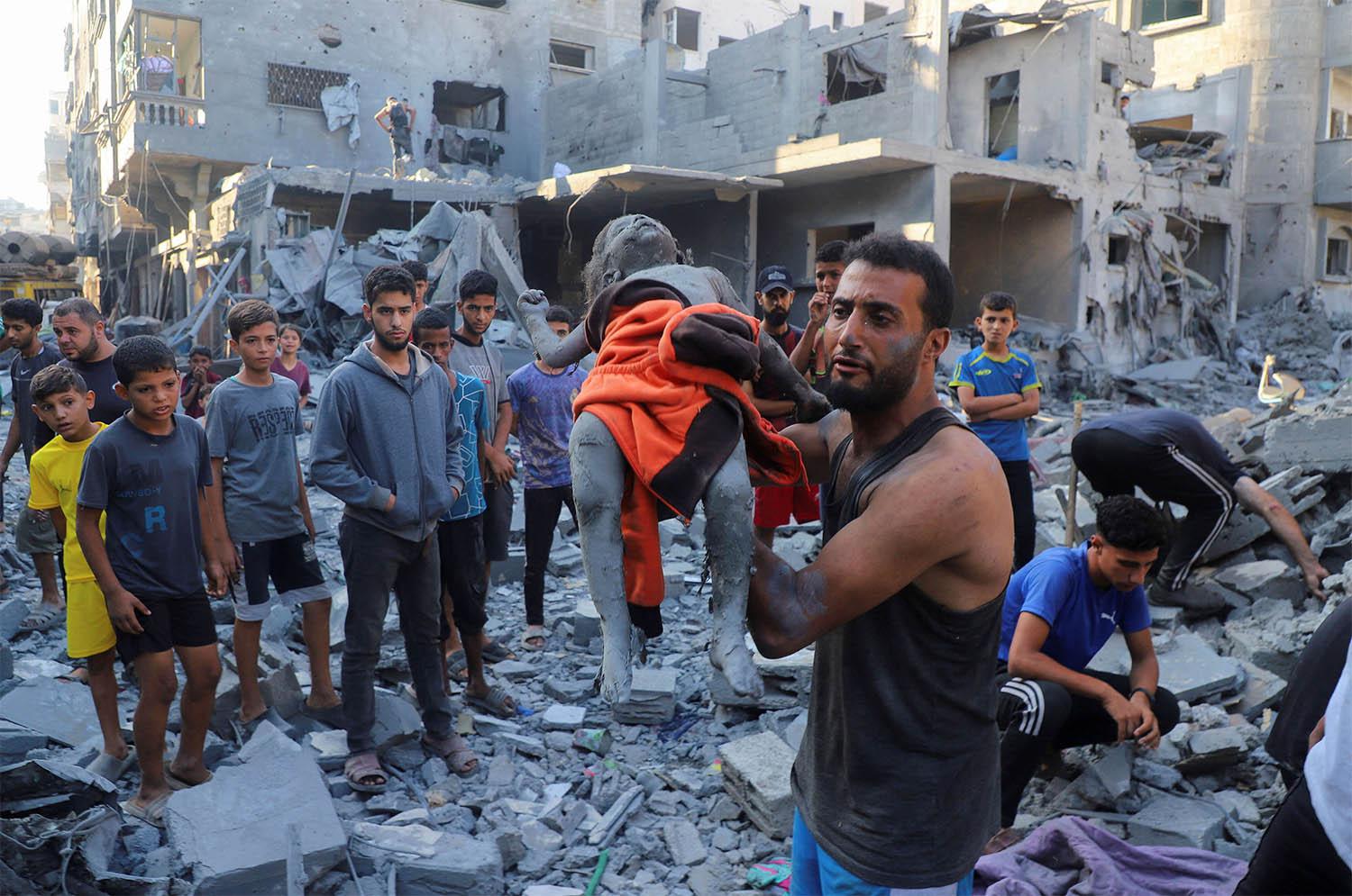 A man carries the body of Palestinian girl Amal Zakot, who was killed in an Israeli strike on a house in Gaza City