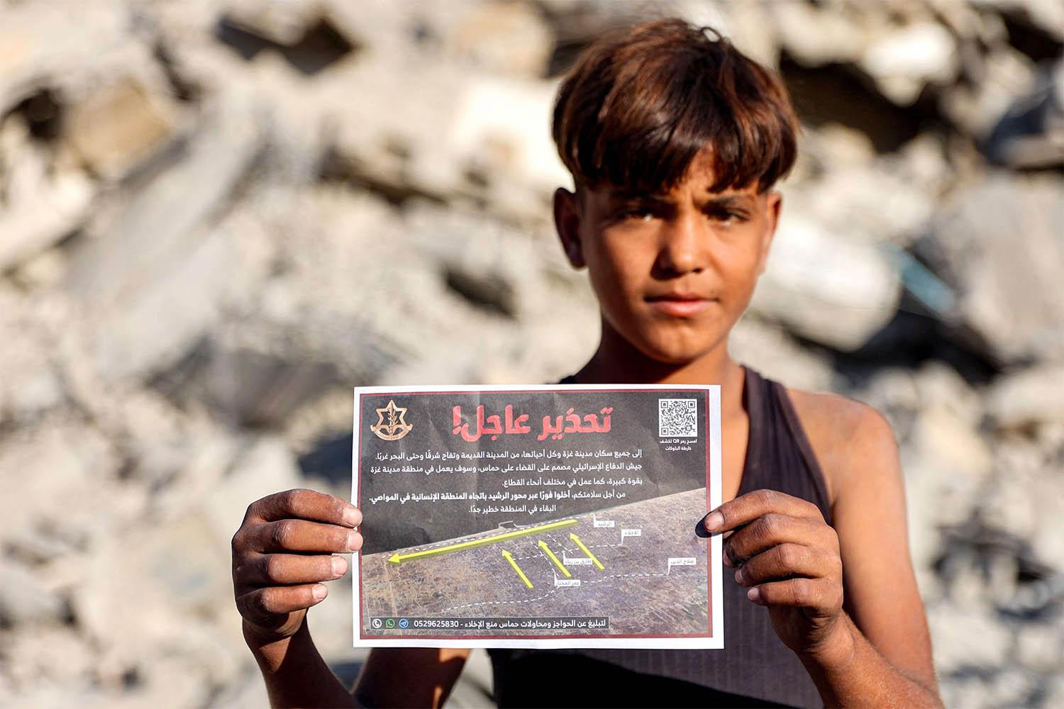 A boy holds one of the leaflets dropped by the Israeli military on Gaza City, urging evacuation south to al-Mawasi