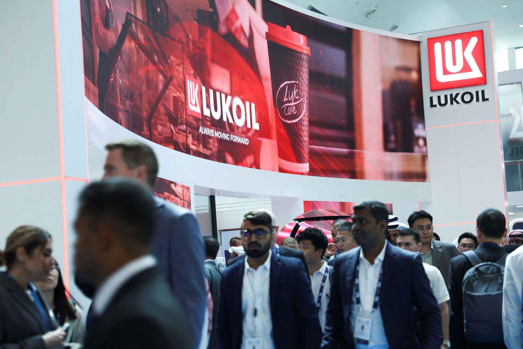 People walk past the booth of Lukoil during the annual energy industry event Abu Dhabi International Petroleum Exhibition and Conference (ADIPEC) in Abu Dhabi, November 3, 2025. 