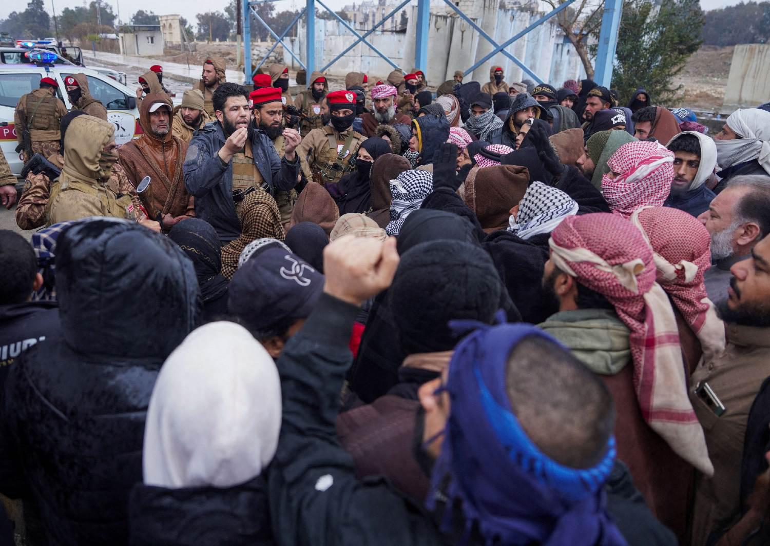 A member of Syrian military police speaks to relatives of detainees gather near al-Aqtan prison in Raqqa