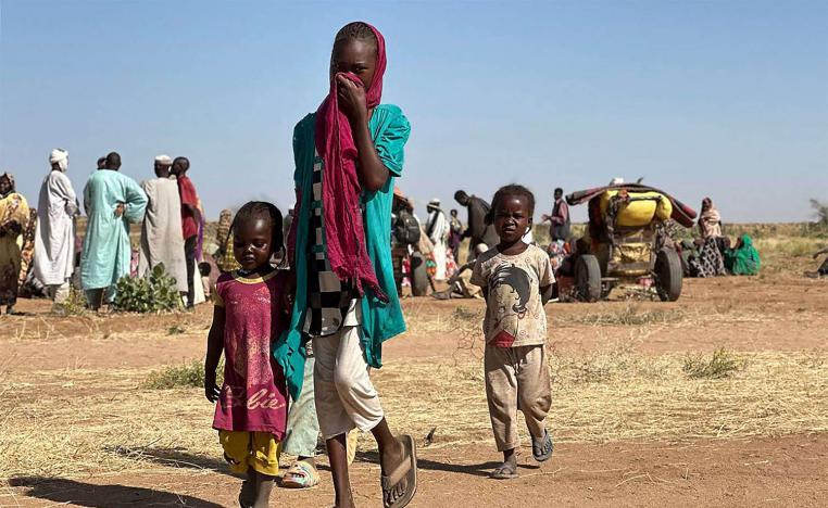 A displaced Sudanese woman, accompanied by children, walks at a camp near the town of Tawila in North Darfur